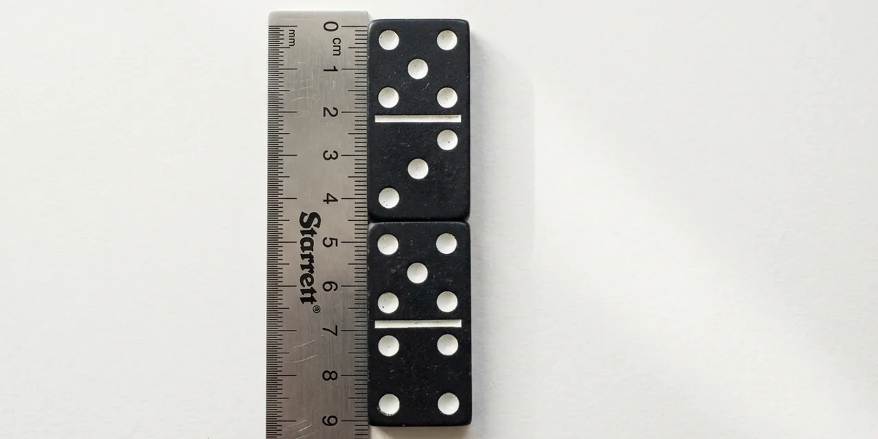 Two dominoes next to a steel ruler, measuring ~10 cm (100 mm)