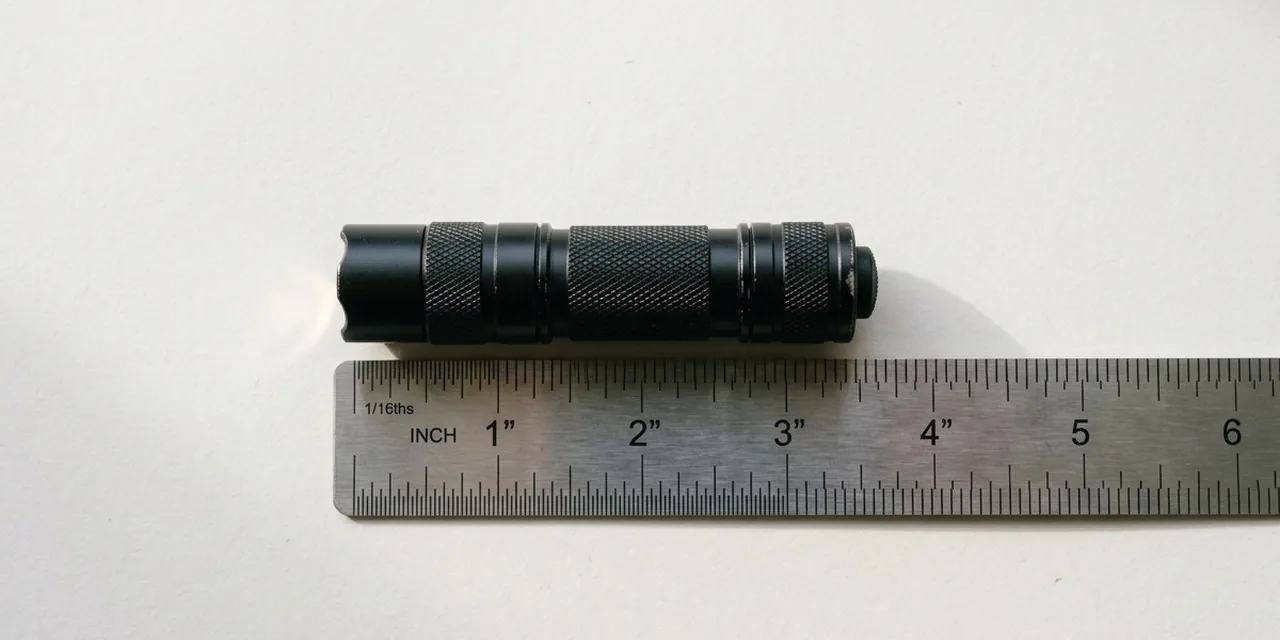 Mini flashlight next to a steel ruler, measuring ~3 in (76 mm)
