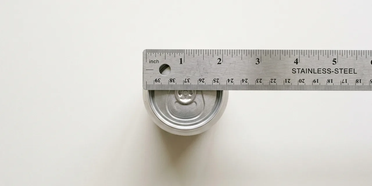 Soda can next to a steel ruler, measuring 2.6 in (66 mm)